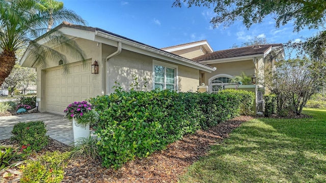 view of home's exterior with an attached garage, driveway, a lawn, and stucco siding