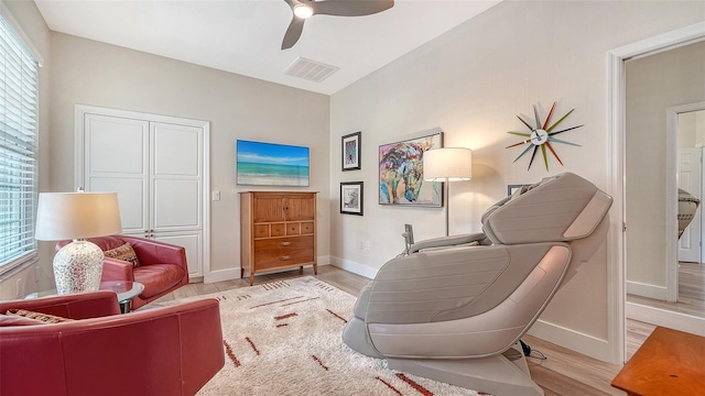 living area featuring light wood-style floors, a ceiling fan, visible vents, and a wealth of natural light