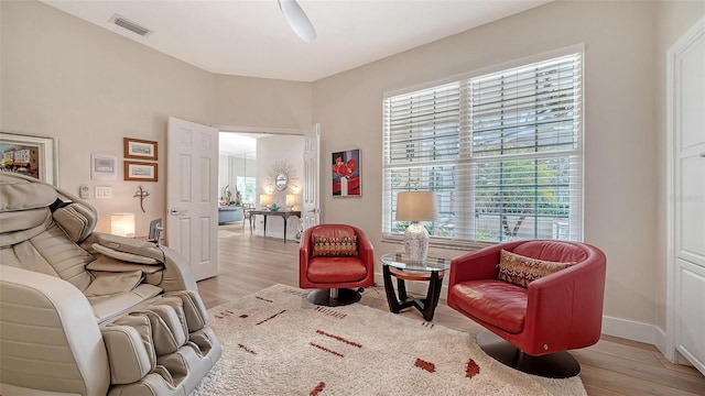 living area featuring light wood-type flooring, visible vents, ceiling fan, and baseboards