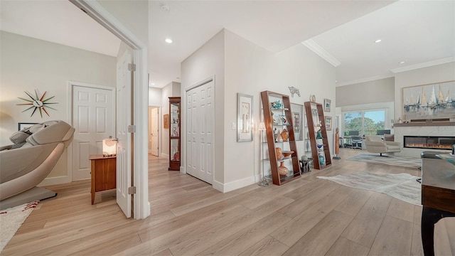 hallway with light wood-type flooring, crown molding, baseboards, and recessed lighting