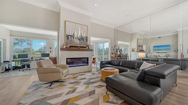 living area featuring ornamental molding, a wealth of natural light, light wood-style flooring, and a towering ceiling