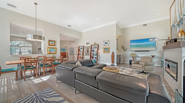 living room with baseboards, visible vents, ornamental molding, light wood-style floors, and a fireplace