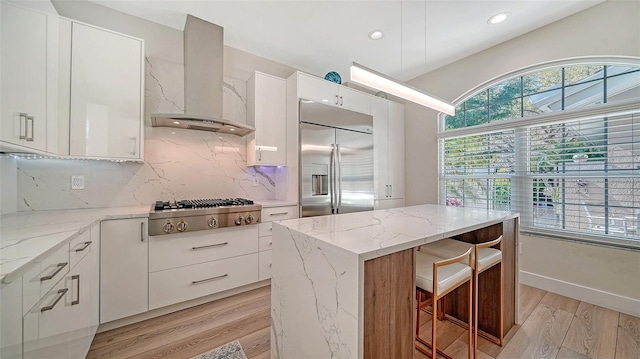 kitchen featuring stainless steel appliances, a kitchen island, white cabinetry, wall chimney exhaust hood, and modern cabinets