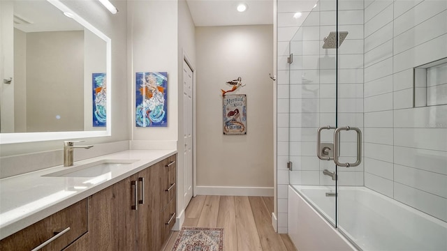 full bathroom with bath / shower combo with glass door, vanity, baseboards, and wood finished floors