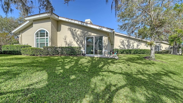 rear view of house with a yard and stucco siding