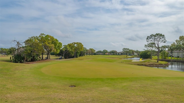 view of home's community with a water view, a yard, and golf course view