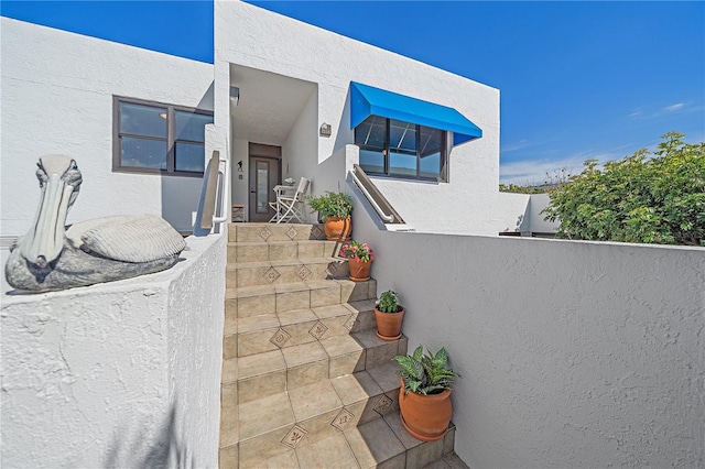 doorway to property featuring fence and stucco siding