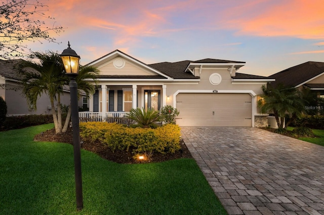 view of front of house with a porch, an attached garage, decorative driveway, stucco siding, and a front yard