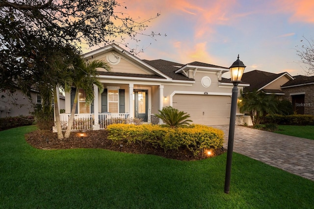 view of front of house with a garage, decorative driveway, a yard, and a porch