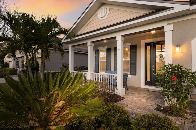 exterior entry at dusk with a porch and stucco siding