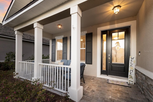 exterior entry at dusk with a porch and stucco siding