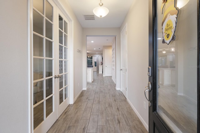 hall with french doors, wood finished floors, visible vents, and baseboards