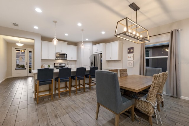 dining area featuring wood tiled floor, visible vents, baseboards, and recessed lighting