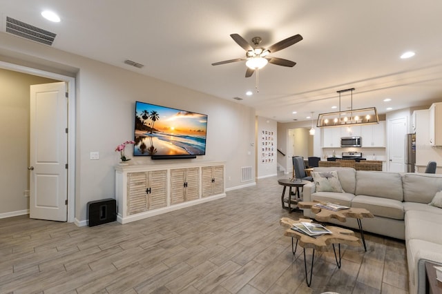 living room with light wood finished floors, visible vents, and recessed lighting