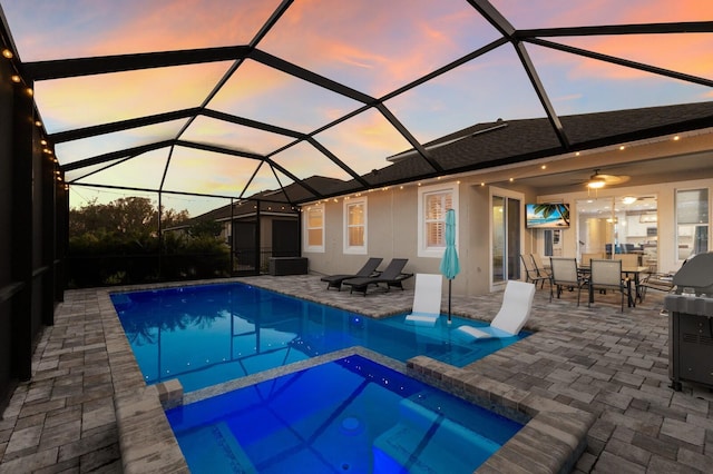 view of swimming pool with glass enclosure, a pool with connected hot tub, a patio area, and outdoor dining area