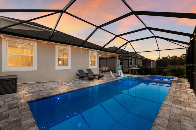 pool at dusk featuring a lanai, a pool with connected hot tub, and a patio