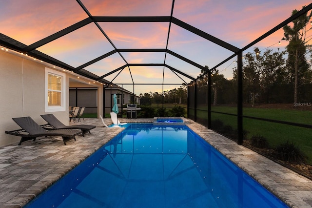 view of pool featuring glass enclosure, a patio area, a pool with connected hot tub, and a grill