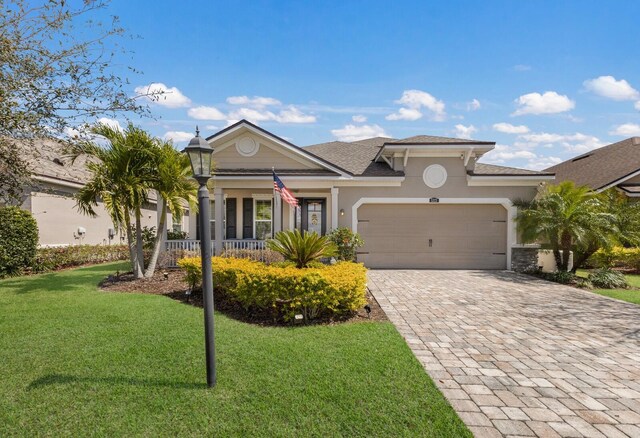 view of front of home with a front lawn, decorative driveway, an attached garage, and stucco siding