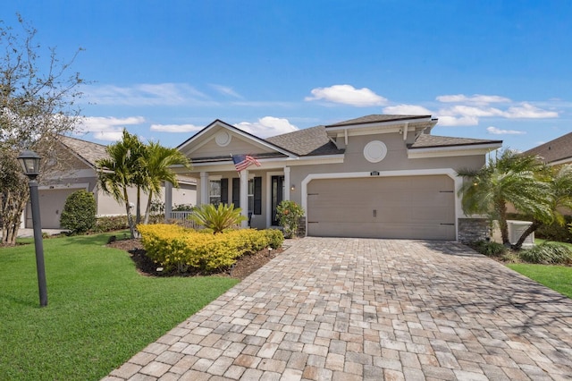 view of front of property featuring a garage, decorative driveway, a front yard, and stucco siding