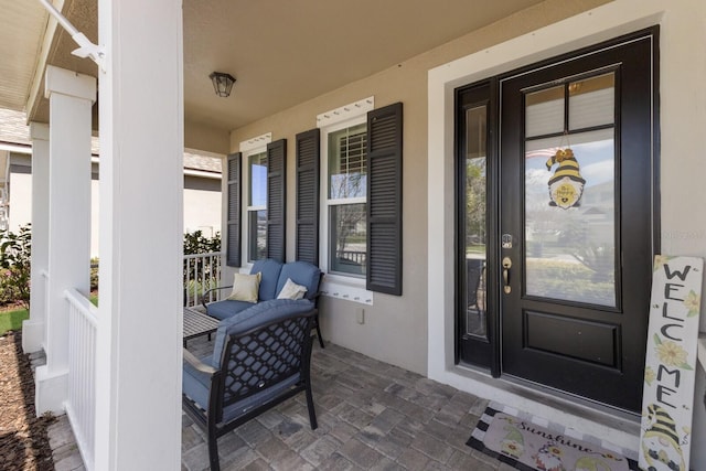 entrance to property featuring covered porch and stucco siding