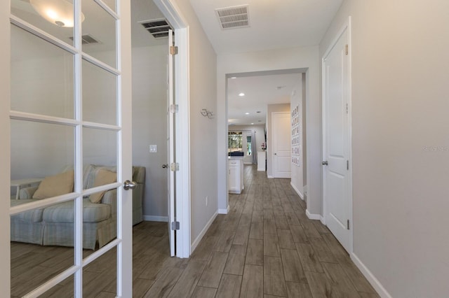 hallway featuring wood finish floors, visible vents, baseboards, and recessed lighting