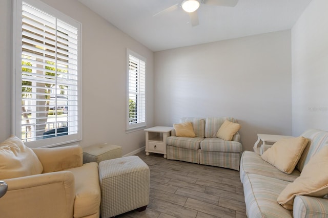 living area featuring a ceiling fan, wood tiled floor, and baseboards