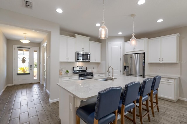 kitchen featuring a sink, visible vents, appliances with stainless steel finishes, tasteful backsplash, and a kitchen bar