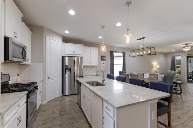 kitchen featuring stainless steel appliances, a sink, open floor plan, tasteful backsplash, and a kitchen bar