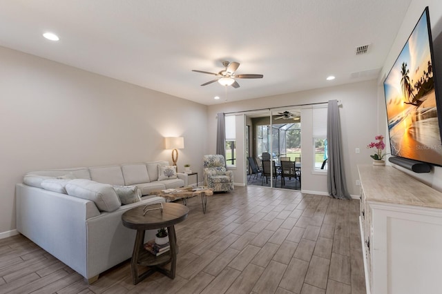 living area with baseboards, wood tiled floor, visible vents, and a ceiling fan