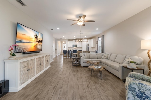 living room featuring ceiling fan, light wood finished floors, visible vents, and recessed lighting