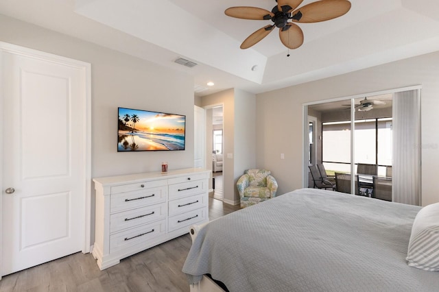 bedroom with access to exterior, a raised ceiling, visible vents, wood finished floors, and baseboards