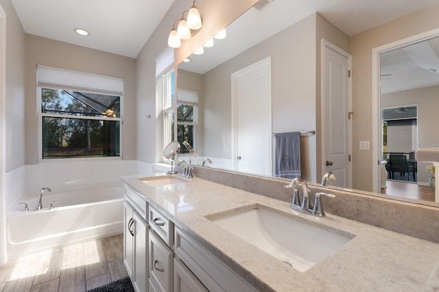 full bathroom featuring a garden tub, double vanity, wood finished floors, and a sink