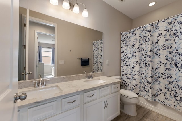 bathroom with double vanity, a sink, toilet, and shower / tub combo with curtain