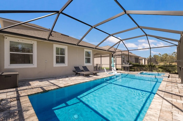 view of pool with glass enclosure, a pool with connected hot tub, grilling area, and a patio