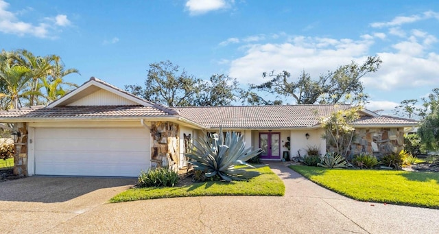 ranch-style house featuring an attached garage, a tile roof, stone siding, french doors, and driveway