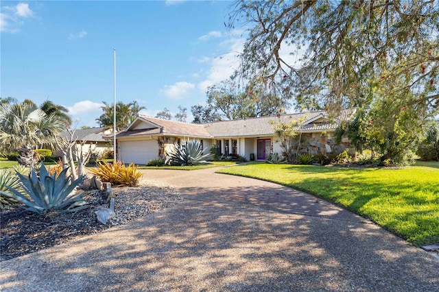 view of front of property featuring driveway, a front lawn, an attached garage, and a tile roof