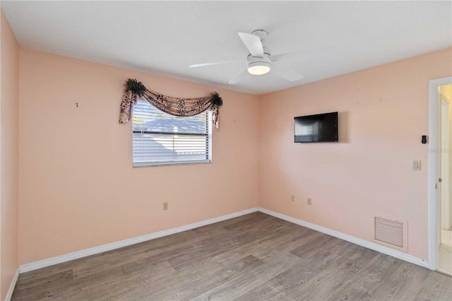 spare room featuring a ceiling fan, light wood-type flooring, visible vents, and baseboards