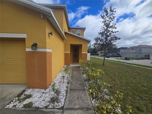 view of property exterior with a yard, an attached garage, a residential view, and stucco siding