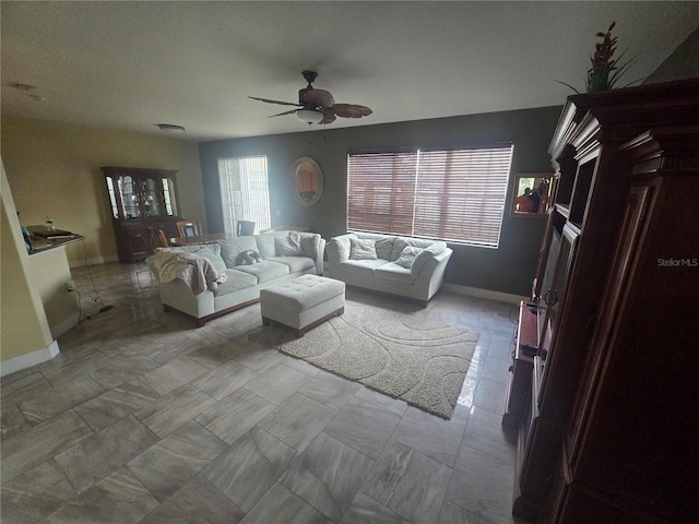 living area with ceiling fan and baseboards