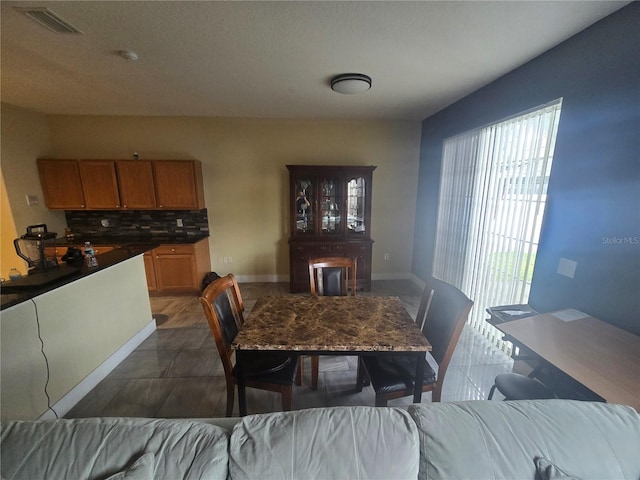 dining area featuring dark tile patterned flooring, visible vents, and baseboards