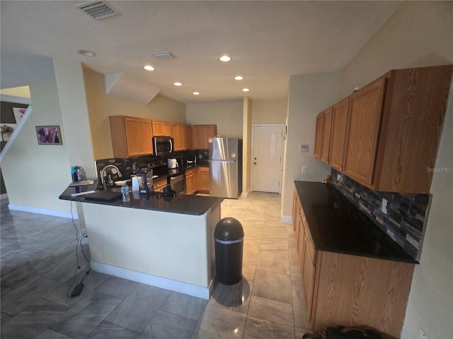 kitchen with stainless steel appliances, dark countertops, visible vents, decorative backsplash, and a peninsula