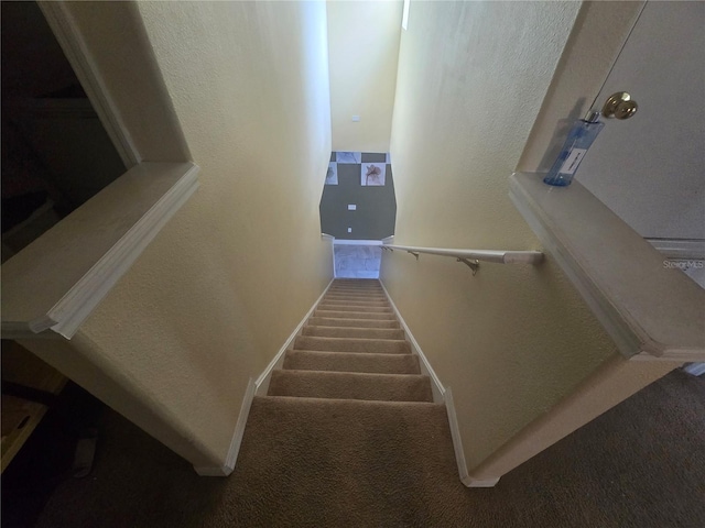 staircase featuring carpet, baseboards, and a textured wall