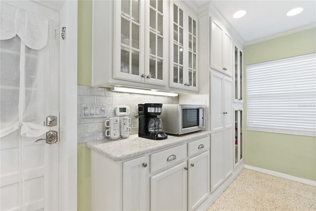 bar with light speckled floor, baseboards, tasteful backsplash, stainless steel microwave, and crown molding