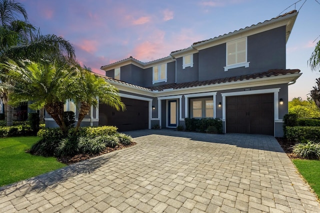 view of front of house featuring a garage, a tile roof, decorative driveway, and stucco siding