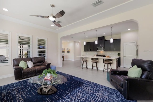 living area with light tile patterned floors, visible vents, arched walkways, and ceiling fan