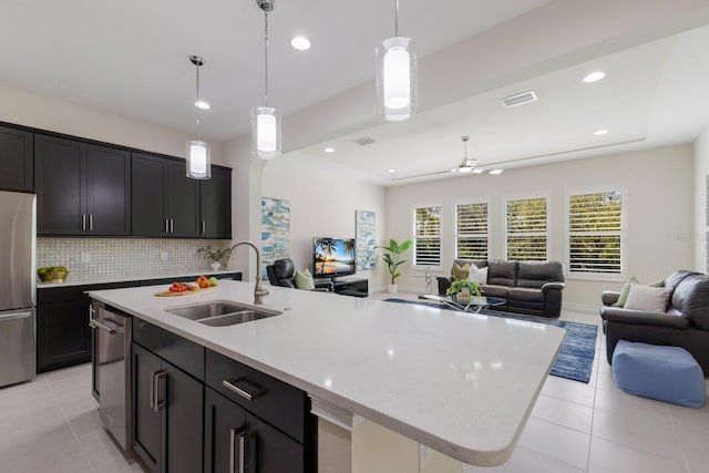 kitchen with stainless steel appliances, open floor plan, a sink, and light tile patterned floors