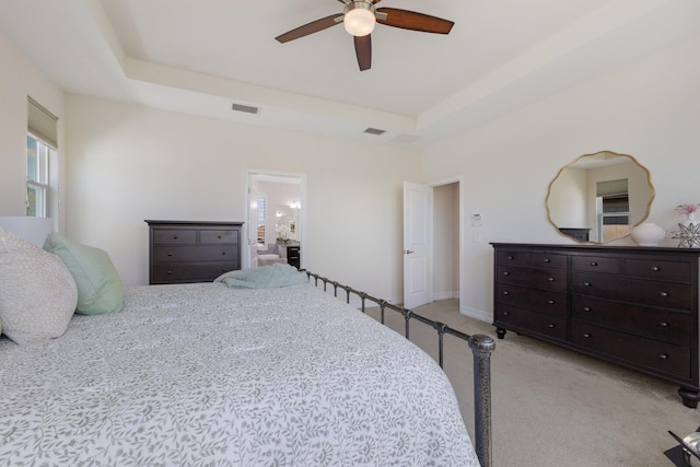 bedroom with a ceiling fan, a raised ceiling, visible vents, and light colored carpet