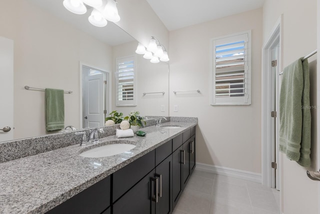 bathroom featuring double vanity, tile patterned flooring, baseboards, and a sink