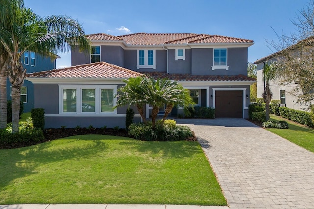 mediterranean / spanish house with a garage, decorative driveway, a tile roof, and stucco siding