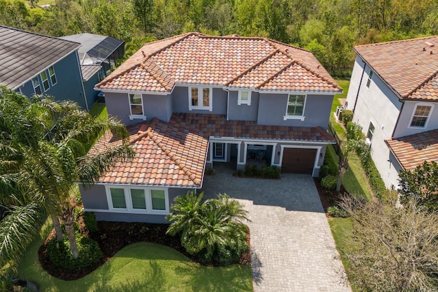 view of front of property featuring a garage, decorative driveway, a tiled roof, and stucco siding